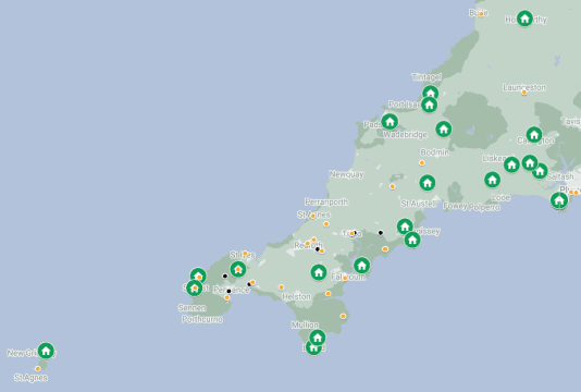A map of Cornwall and the Isles of Scilly featuring 23 green home icons representing completed CLT builds. These are scattered across Cornwall, including Lizard, Ruan Minor, Tintagel, St Just, Lands End Peninsula, Nancledra, Park Pedrek & Park Wella, St Just in Roseland, St Goran, St Ewe, Luxulyan, St Minver, Blisland, st Teath, Delabole, Duloe, Menheniot, Blunts, Landrake, Millbroke, Kelly Bray, Bradwrothy. 